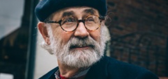 Man with grey beard, flat cap and glasses