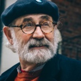 Man with grey beard, flat cap and glasses